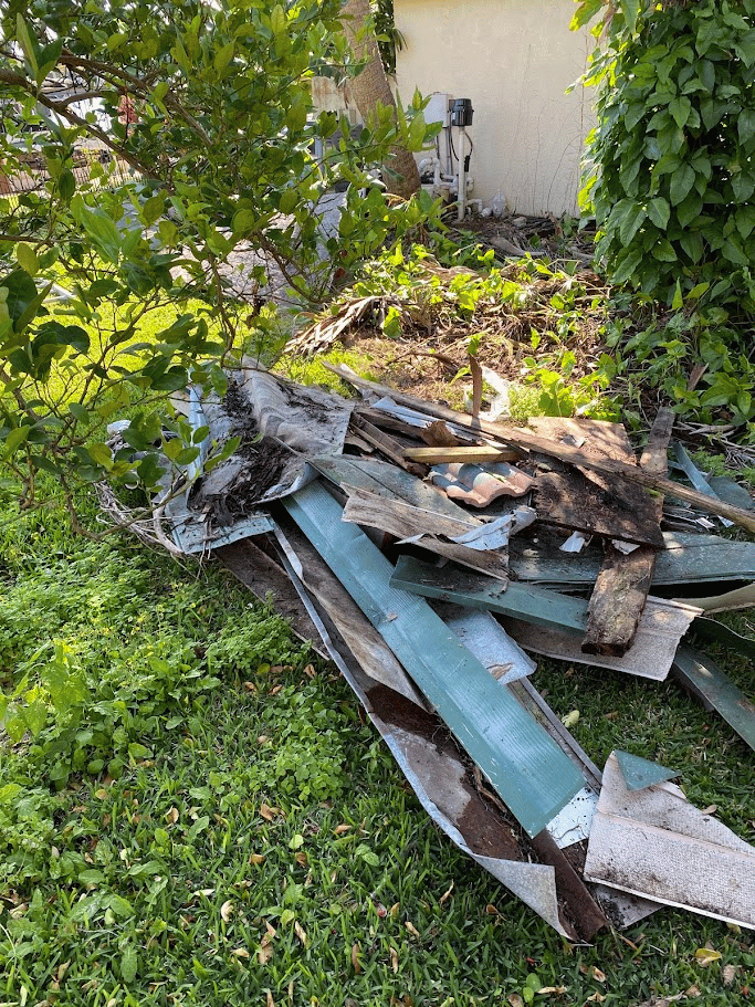 Stack of discarded wood and outdoor materials gathered near a residential yard